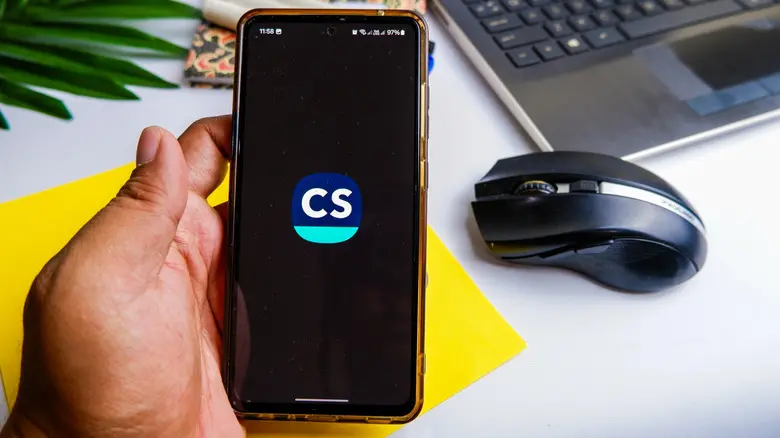 آقایی که گوشی را در دست دارد و لوگوی CamScanner را بر صفحه نمایش نشان میدهد