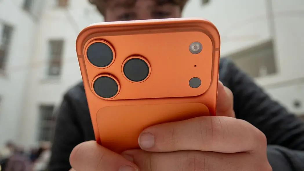 شخصی که آیفون ۱۷ پرو به رنگ نارنجی در دست دارد