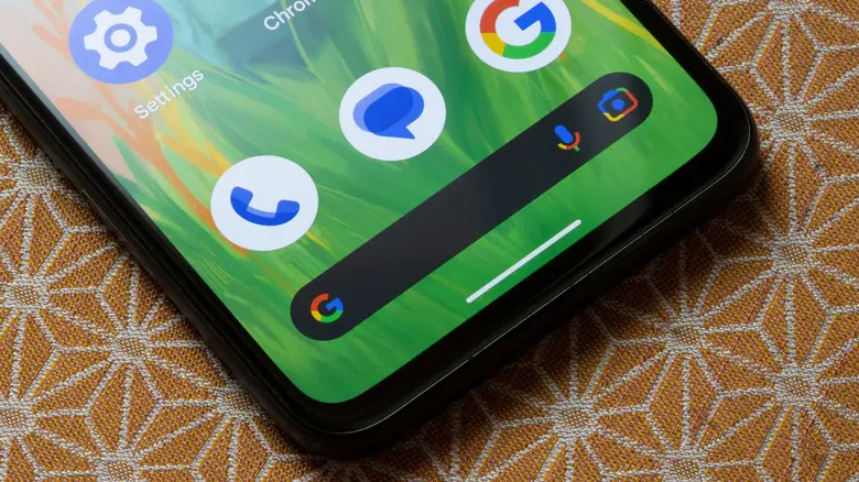 یک تلفن هوشمند اندروید گوگل که روی یک میز طرحدار قرار دارد، صفحهٔ اصلی اندروید را نمایش میدهد و بر روی یک ویجت گوگل متمرکز است
