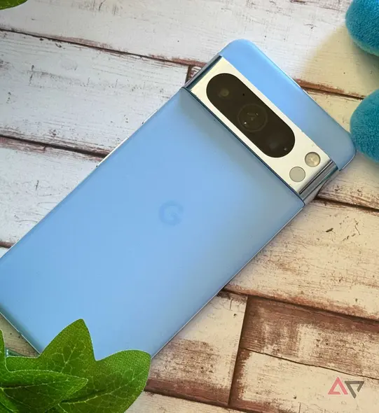 Google Pixel 8 Pro که در کنار یک گیاه مصنوعی و یک عروسک نرم قرار دارد