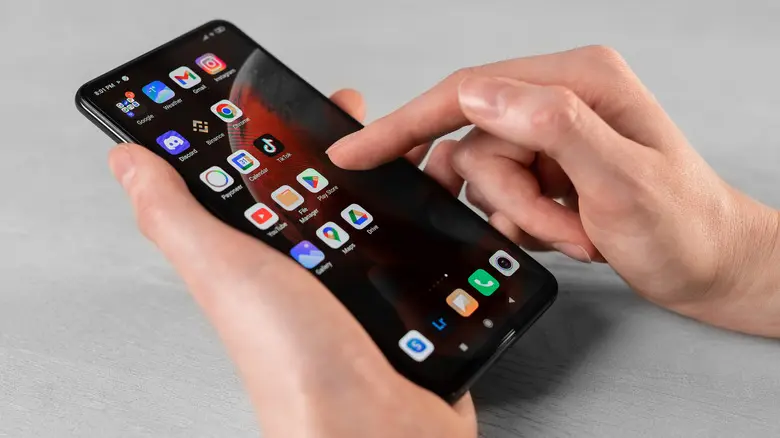 شخصی که گوشی اندروید در دست دارد و برنامهها روی صفحه نمایش داده شدهاند