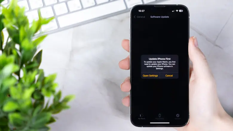 دستی که یک آیفون را نگه داشته و صفحهی بهروزرسانی نرمافزار را نمایش میدهد.