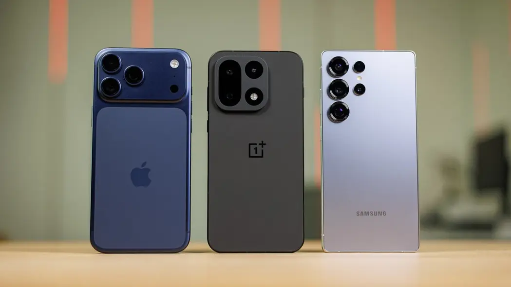 گوشی‌های iPhone 17 Pro Max، OnePlus 15، و Samsung Galaxy S25 Ultra که کنار هم ایستاده‌اند.