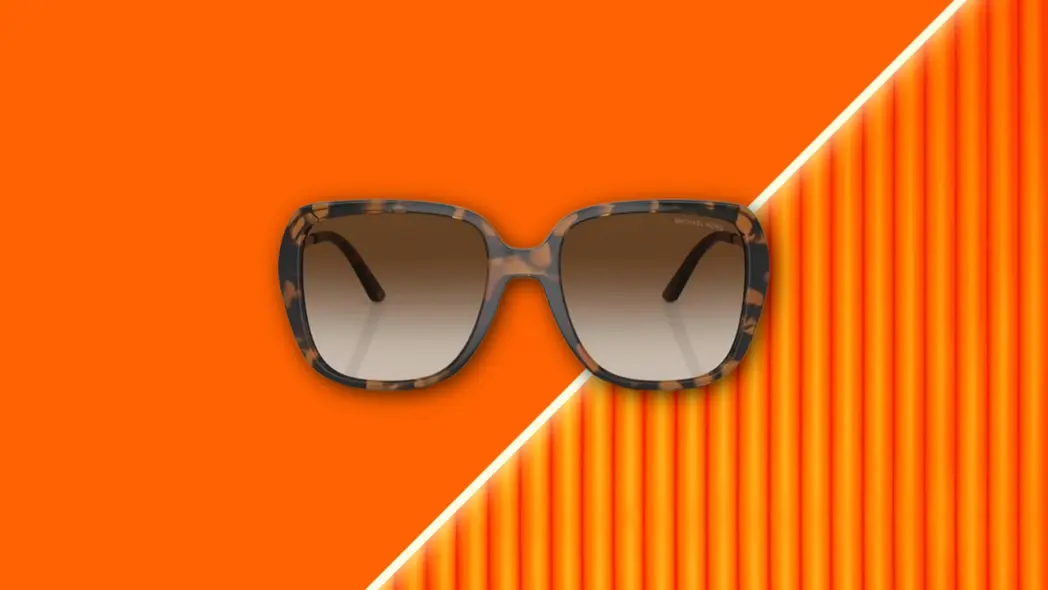 عینک آفتابی Michael Kors که بر پسزمینه نارنجی زنده شناور است