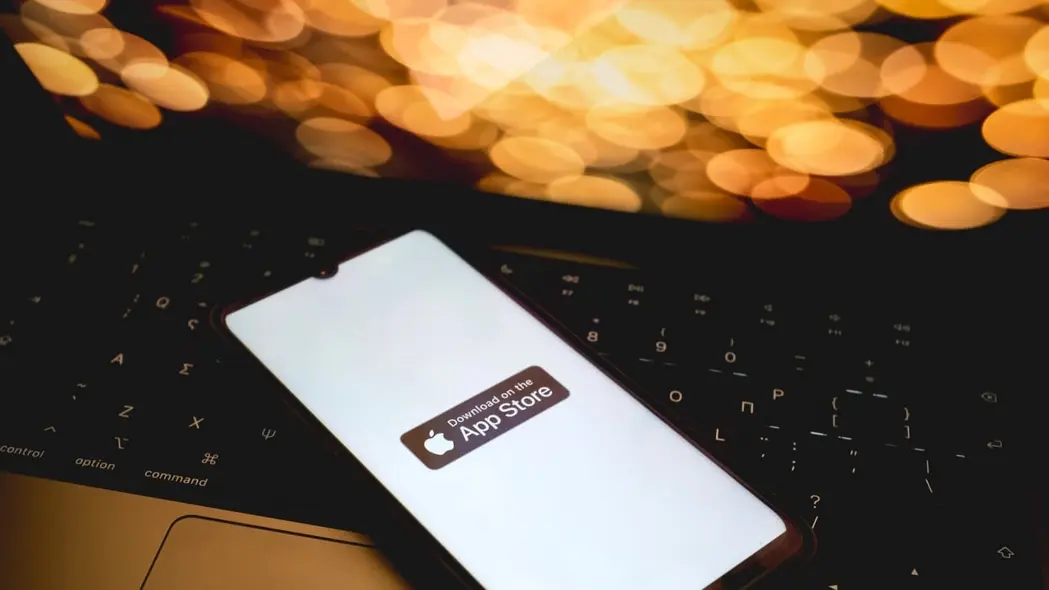 اپاستور روی یک آیفون در بالای یک لپتاپ.