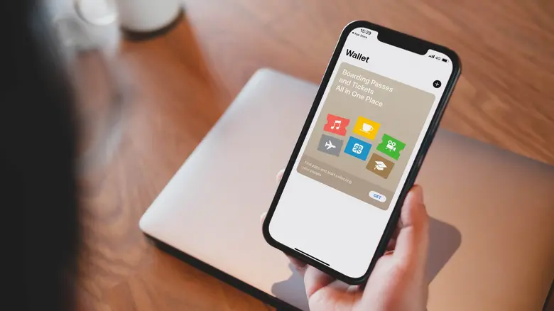 شخصی که آیفون خود را در دست دارد و برنامه Apple Wallet را نشان می‌دهد
