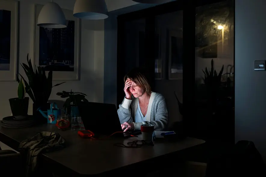 زنکی که به‌صورت غمگین به لپ‌تاپ نگاه می‌کند