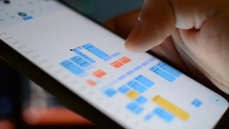 دستی که تلفن همراهی را نگه داشته و برنامه تقویم گوگل را نشان می‌دهد