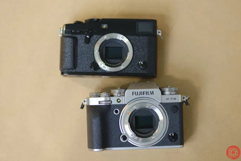 دو دوربین بدون لنز فوجیفیلم بدون آینه بر روی سطح بژ، یکی سیاه و دیگری نقرهای-سیاه.