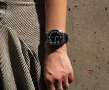 ساعت هوشمند سامسونگ Galaxy Watch 8 Classic بر روی مچ دست، جلوی دیوار بتنی