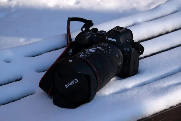 دوربین Canon EOS R6 روی یک نیمکت چوبی پوشیده از برف قرار دارد، که به‌جز آن بخشی از برف‌پوشیده است.