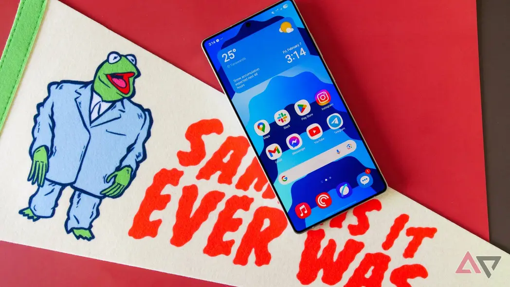 Galaxy S25 Ultra با صفحهٔ اصلی‌اش نمایش داده شده، بر روی پرچمی که نوشتهٔ «همان‌طور که همیشه بوده است» دارد، قرار گرفته است